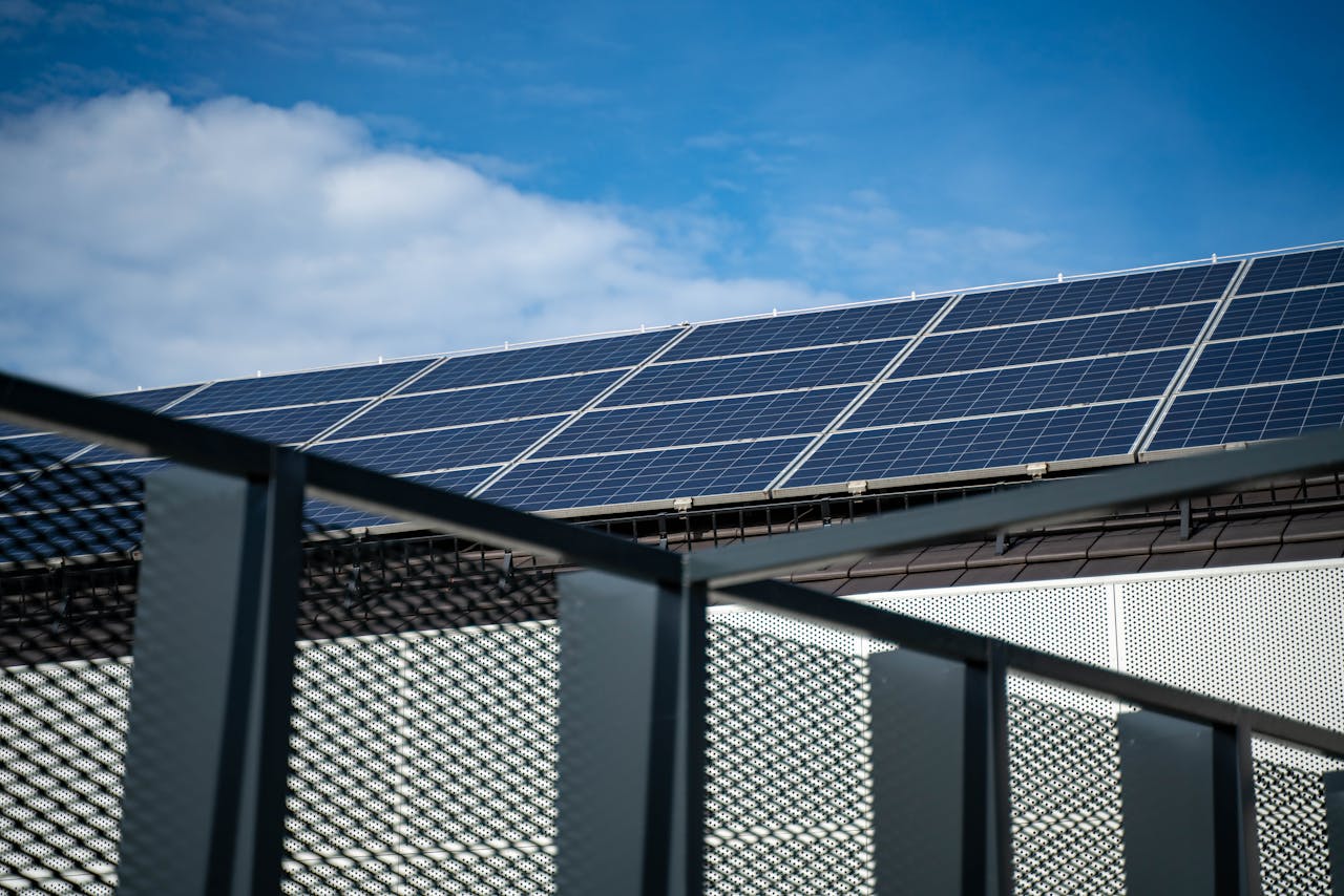 hero-img-01 Close-up view of modern solar panels on a rooftop against a clear blue sky, representing clean energy.