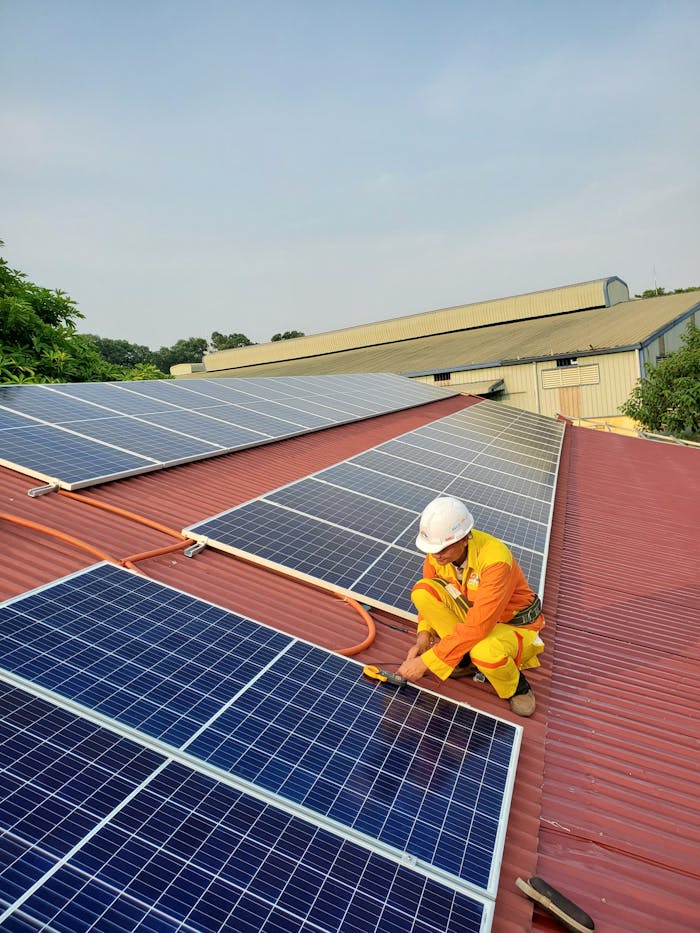 why-choose-us Technician working on solar panel installation on a rooftop under clear sky.
