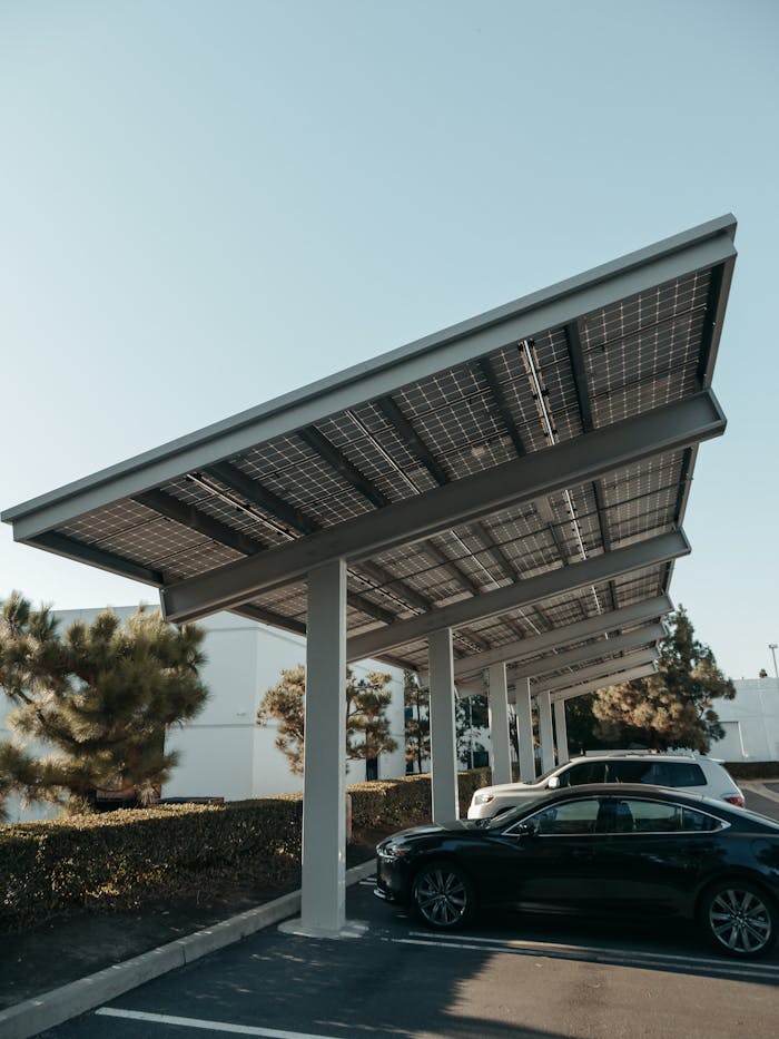 contact-img Cars parked under solar panel structures in a modern parking lot utilizing renewable energy.