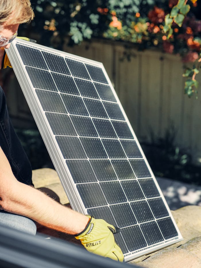services-02 A worker installs a solar panel in a garden, promoting clean energy.